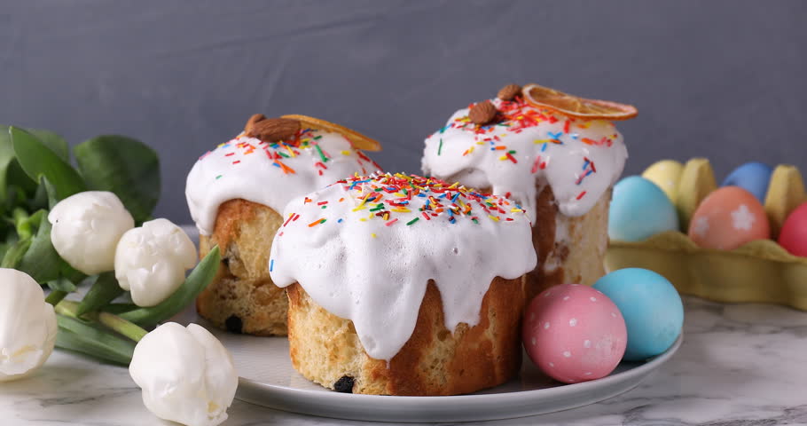 Woman decorating delicious Easter cake with dried orange slice at table, closeup