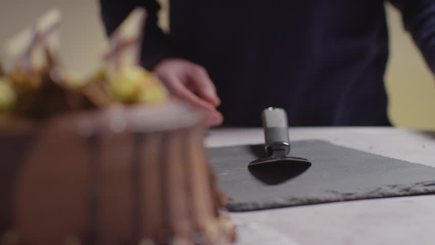 Person slicing chocolate cake with spatula on slate plate