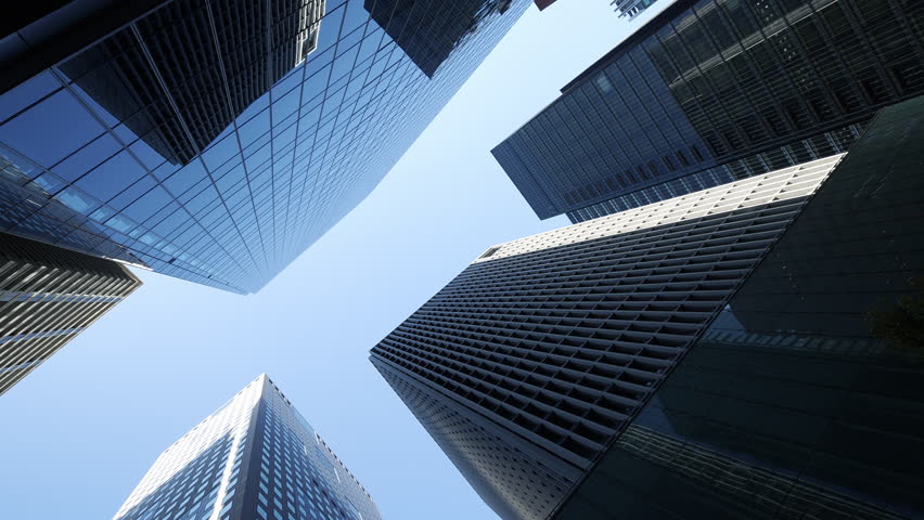 Abstract perspective of massive glass skyscrapers reaching into a clear sky.