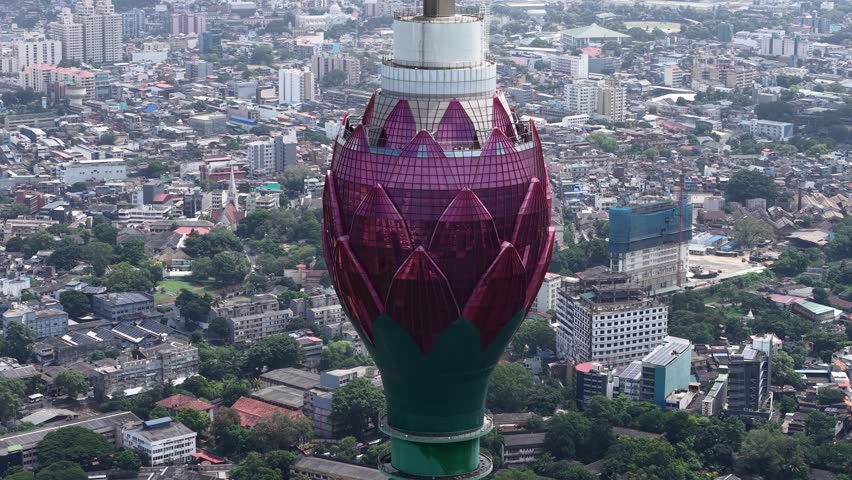 Majestic drone orbit circling the iconic pink glass petals of the Lotus Tower in Colombo, revealing the dense Sri Lankan cityscape, 4K.