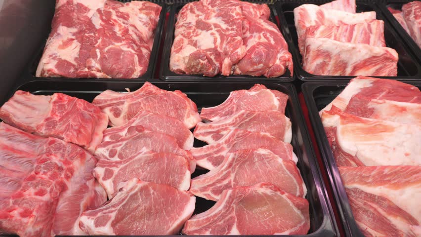 Close-up of various raw meats on a cutting board, highlighting texture, color, and freshness, ideal for culinary, food preparation, or butchery themes.