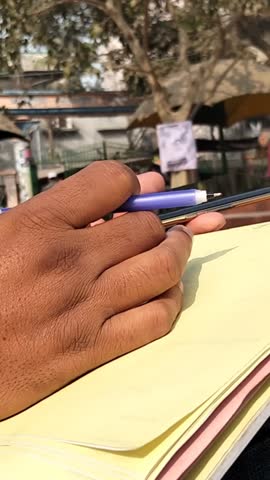 Close-Up of Hand Writing on Paper with Pen in Public Place