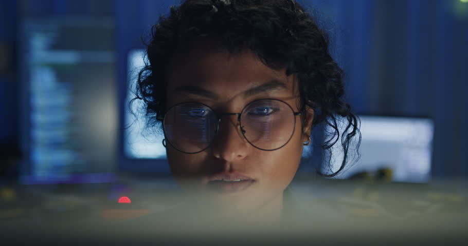 Close-up Black female programmer with code reflection in glasses working late in home office at night. Cybersecurity, AI algorithm, Network security, software developer, serious face, burnout concept.
