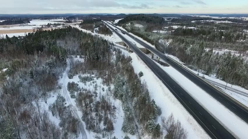 Aerial View of Snow-Covered Highway Surrounded by Lush Green Forest and Winter Landscape in Finland
