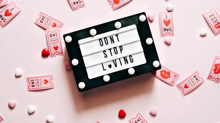 Romantic flat lay featuring a lightbox light message with confetti hearts surrounded by Be My Valentine decorations. Perfect for love, celebration, and holiday concepts