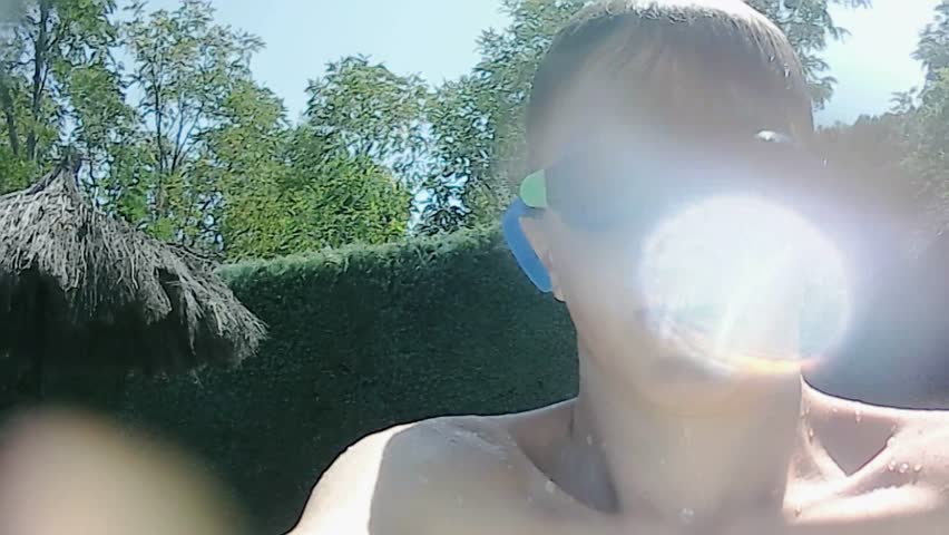 Young boy with swimming goggles jumping into a pool and submerging underwater with bubbles