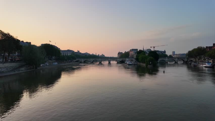 Beautiful parisian cityscape showing the calm seine river at twilight with the pont neuf and île de la cité in the background, creating a romantic and serene atmosphere in the french capital