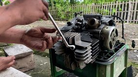 Wonogiri, indonesia - 2,1,2026 : Close-up footage of hands repairing a motorcycle engine using tools, showing mechanical work, maintenance process, and automotive repair concept in outdoor setting. - Powered by Shutterstock - Get 15% off with code: PIKWIZARD15