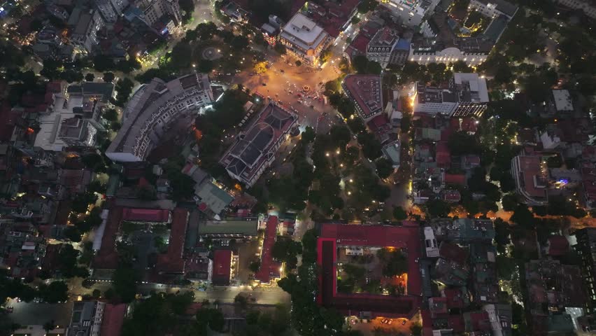 Bustling Hanoi cityscape captured in an aerial orbit shot at night, showcasing illuminated streets, busy traffic, and glowing urban architecture in Vietnam.