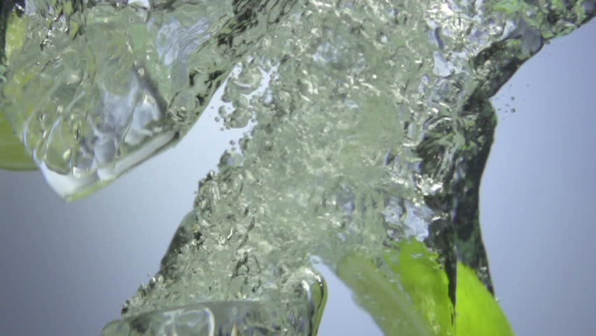 Fresh lime dropped into water with splash