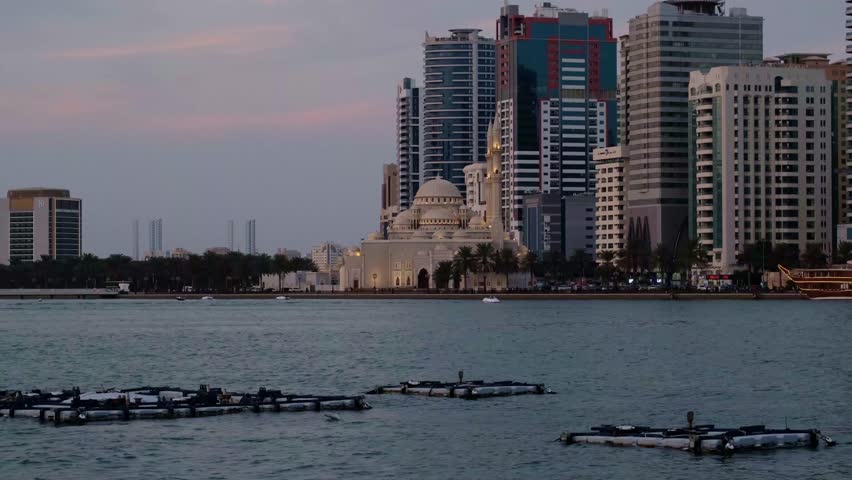 Sharjah Creek, a view of skyscrapers and the sea at sunset. A popular tourist destination in Dubai. Boats sail along the creek. Skyscrapers are caught in the rays of the setting sun.