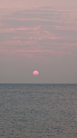 Sunrise sun shining over sea waters with rippled waves moving in slow motion captured in vertical format