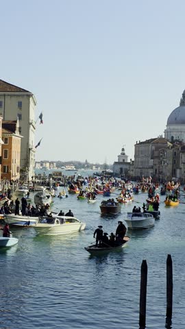 February 1,2026.Venice,Italy.  Vibrant water parade during the Venice Carnival. Many traditional boats and gondolas with people in costumes rowing on the Grand Canal against the backdrop of the Basilica di Santa Maria della Salute in Venice, Italy