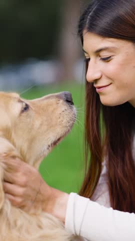 Happy young woman receiving affectionate licks from her beautiful golden retriever dog. Close up of a loving bond between pet and owner
