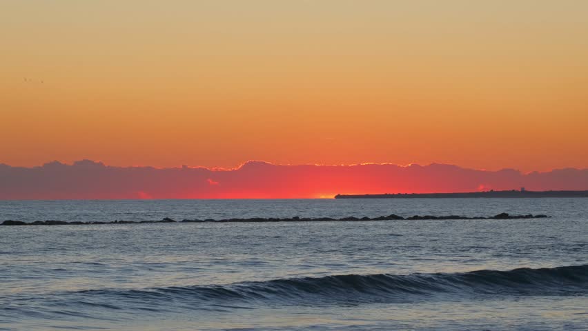Red Sun Setting Over Calm Sea Horizon at Sunset. Golden Evening Sky and Red Sun Above Tranquil Sea. Romantic Tropical Sunset with Sun Descending into Ocean. Scenic Seascape with Bright Red Sun at Dusk
