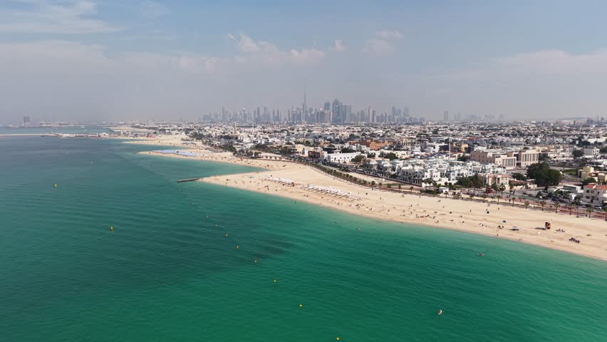Drone approaching Jumeirah Beach with Dubai skyline in the background, UAE