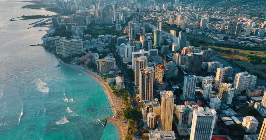 Waves roll to the beach of luxurious Waikiki. Aerial perspective on a beautiful resort at sunset, time.