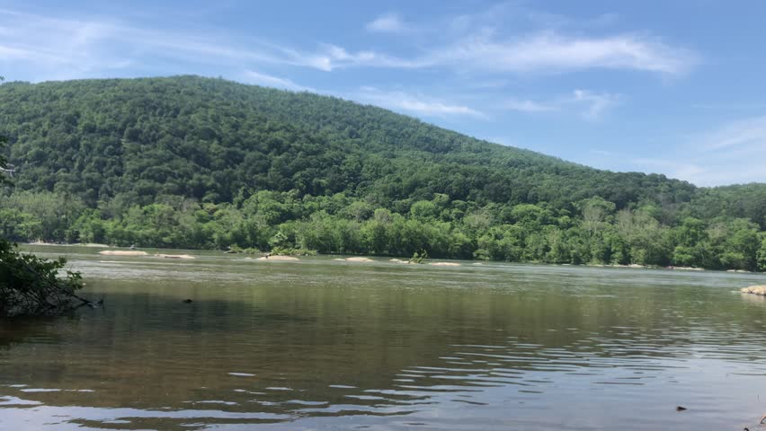 Babbling waters of the Shenandoah River flow past a densely green hill on the opposite bank.