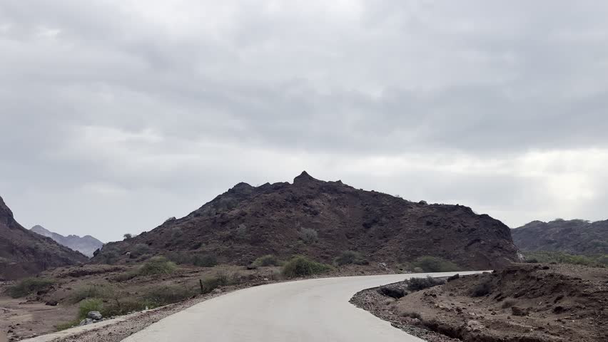 Winding mountain road through rocky hills under cloudy sky
Empty paved road curving through rugged arid mountains and rocky landscape with overcast clouds, scenic travel background.