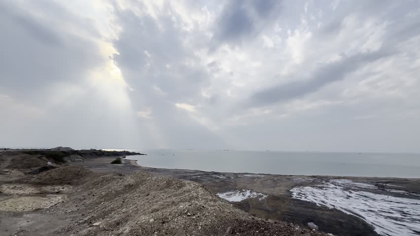 Sun rays breaking through clouds over rocky coast
Dramatic sunbeams shining through cloudy sky over calm sea and rocky shoreline, moody seascape background with copy space.