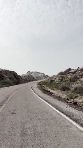 Vertical empty road through rocky mountains under cloudy sky
Vertical shot of an empty asphalt road curving through rocky hills and mountains under a cloudy sky, scenic travel route and wilderness landscape.