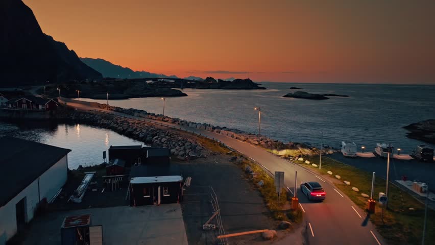 Aerial view of a scenic coastal road in Norway at sunset, capturing dramatic landscapes, ocean views, and stunning natural beauty for travel projects.