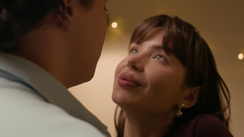 Close up shot of young Caucasian loving couple looking at each other while sharing intimate moment at home