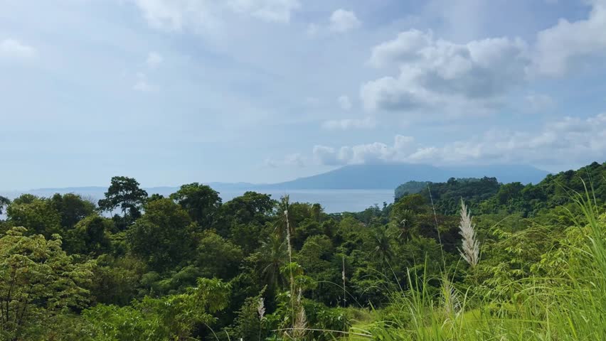 View of beautiful scenery, a mountain, showing turquoise waters, coastal cliffs, and clear sunny skies along the scenic shoreline.