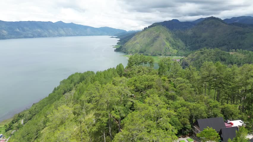 Majestic lake surrounded by lush green trees and mountains under a cloudy sky creating a serene and peaceful atmosphere, showcasing the natural beauty of the landscape with a tranquil lake and majestic mountains in the background.