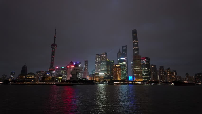 Shanghai, China: Tilt down footage of the light of the famous Shanghai skyline facing the skyscrapers of Pudong financial district reflection in the water the Hangpu river at dusk in China.