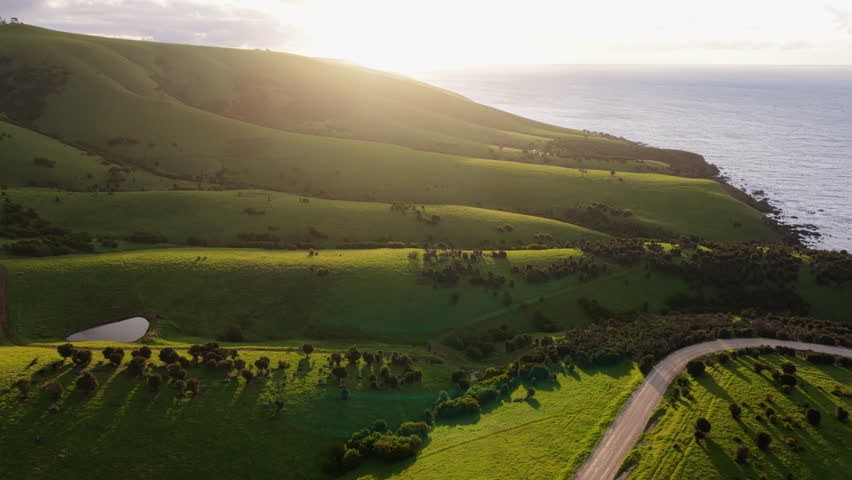 Epic sunset aerial of rolling green coastal hills in Kangaroo Island in South Australia. This lush island is home to great biodiversity and a protected nature reserve in the South Pacific.