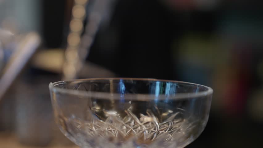 Close up of creamy cocktail poured through mesh sieve into coupe glass