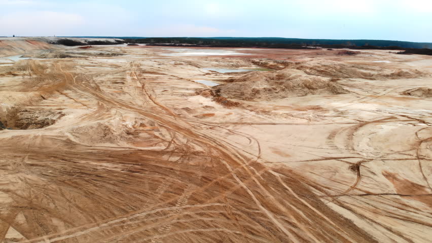Bright Sandy Field With Reflections And Tracks. Sunny Sandy Terrain With Pools And Winding Tire Trails. Media