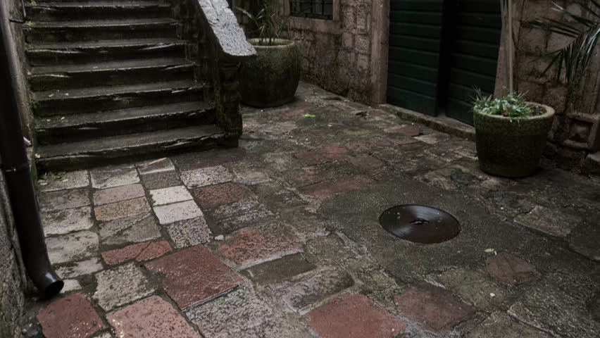 Narrow stone courtyard with a weathered staircase leading upward between aged masonry walls. Old town of Kotor, Montenegro