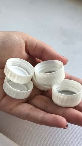 White plastic bottle caps in a woman's hand close-up. The concept of plastic recycling, the use of disposable plastic tableware.