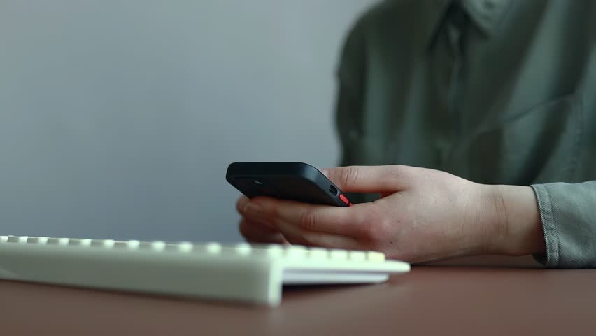 Person holds a smartphone while interacting with digital calendar icons above the device during a work session in an office.