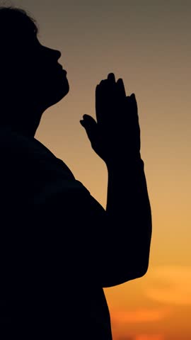 Christian woman praying at sunset, close-up. Forgiveness, Hope, Faith. Girl against skyline in sun