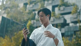 Smart young Asian businessman using smartphone for high-speed 6G video call or online meeting in a modern city. Future technology, wireless communication, and digital connectivity concept. - Powered by Shutterstock - Get 15% off with code: PIKWIZARD15