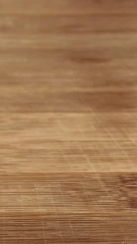 Close-up of a chef slicing a red juicy tomato with a knife on a wooden board