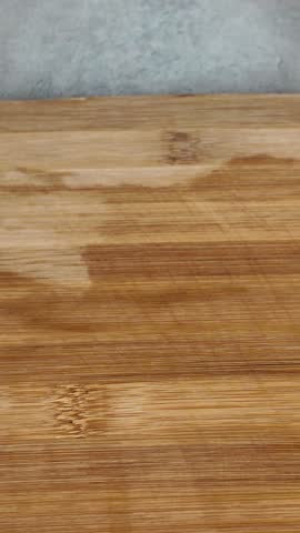 Close-up of female hands with a knife slicing fresh spring onions on a bamboo cutting board. Healthy cooking and meal preparation concept