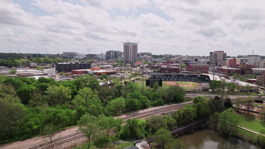 Drone shot wide aerial shot of downtown cityscape of capital city Montgomery, Alabama in deep south of America, including government buildings, riverfront, residential apartments, and car traffic