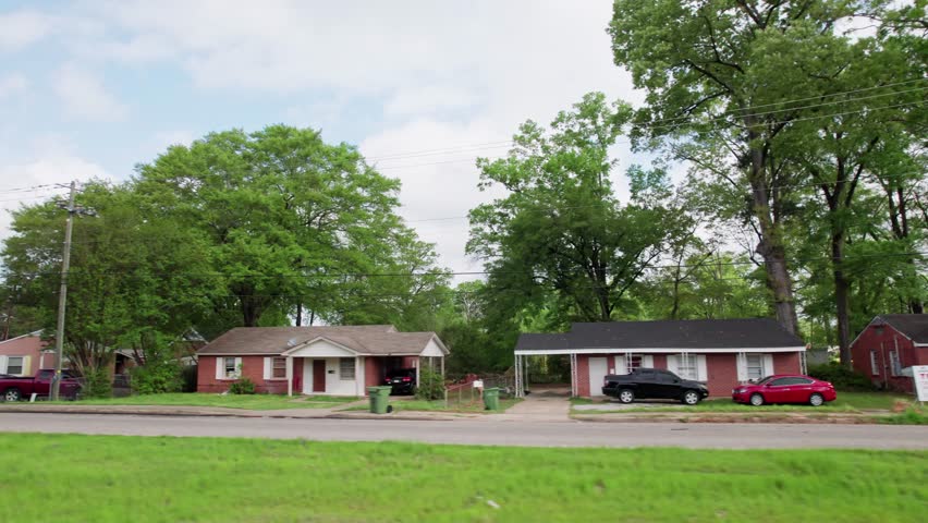 Moving past middle lower class poor neighborhood street homes outside downtown capital city Montgomery, Alabama in historic suburb community with houses, buildings, sidewalk, cars, driveways, and road