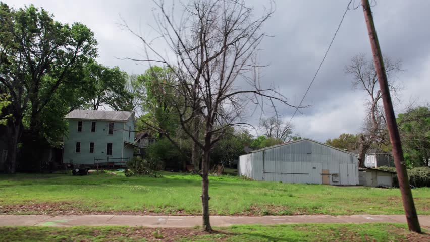 Moving past middle lower class poor neighborhood street homes outside downtown capital city Montgomery, Alabama in historic suburb community with houses, buildings, sidewalk, cars, driveways, and road