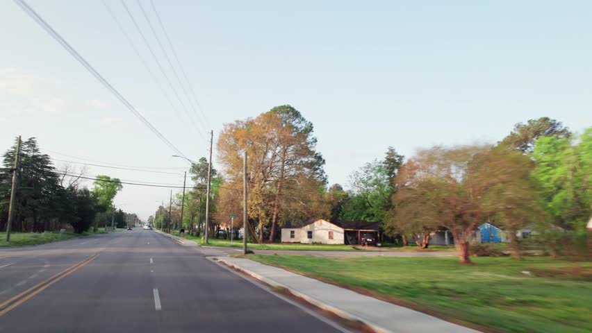 Moving past middle lower class poor neighborhood street homes outside downtown capital city Montgomery, Alabama in historic suburb community with houses, buildings, sidewalk, cars, driveways, and road