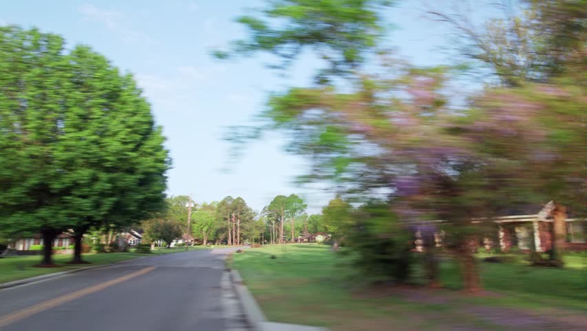 Moving past middle lower class poor neighborhood street homes outside downtown capital city Montgomery, Alabama in historic suburb community with houses, buildings, sidewalk, cars, driveways, and road