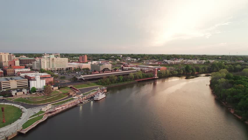 Aerial drone landscape view of downtown Montgomery, Alabama riverfront water park along gun island shoot river with baseball ballpark stadium, green lawn, buildings, high-rises, and capital city roads