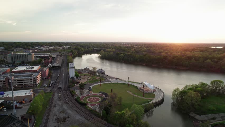 Aerial drone landscape view of downtown Montgomery, Alabama riverfront water park along gun island shoot river with baseball ballpark stadium, green lawn, buildings, high-rises, and capital city roads