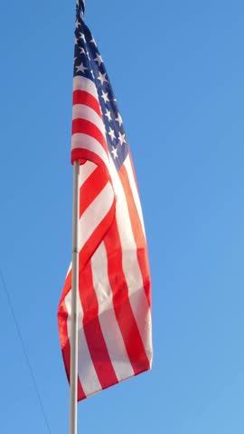 American flag flowing and waving on blue sky background. Nobody