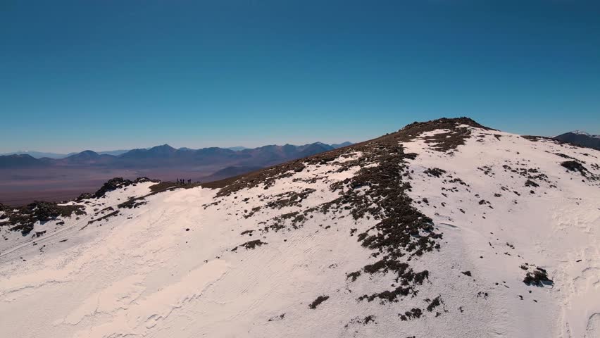 Hikers on snowy mountain peak with breathtaking landscape view