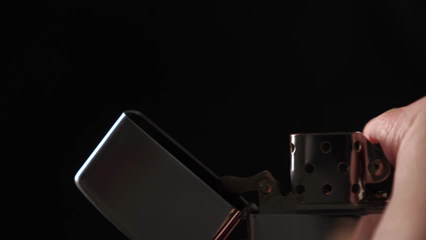 Igniting gasoline lighter with flying sparks on black background, closeup
